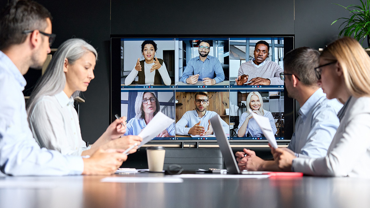 A business team in a meeting room participating in a video conference with remote colleagues.